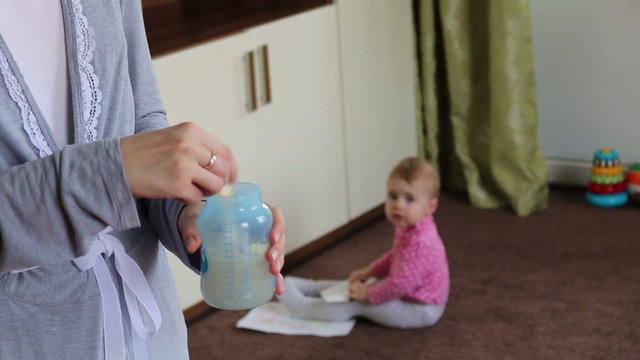 mother preparing milk for your child. baby at background