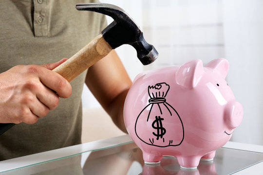 Man with a hammer going to break the piggy bank, close up