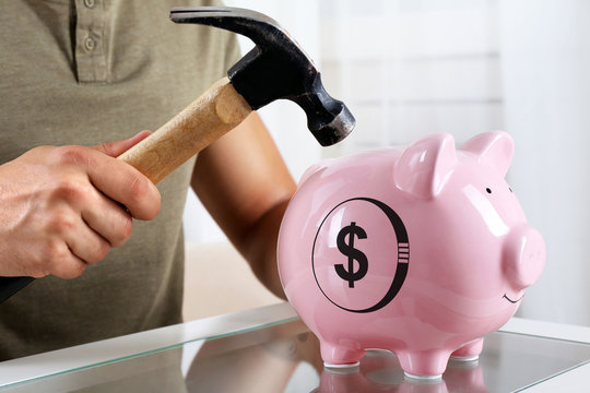 Man with a hammer going to break the piggy bank, close up