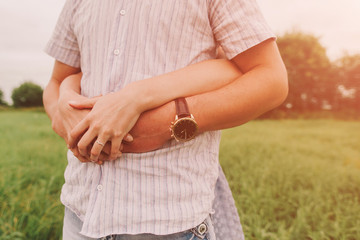 closeup hands of hugging men and women in the field in warm colors