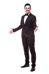 Cheerful young man in suit welcome sign and smiling while standing against white background.Showman...
