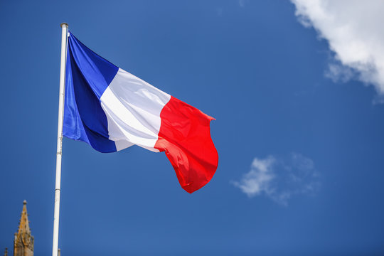 French flag against blue cloudy sky.