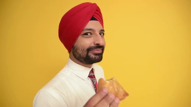 Locked-on shot of a businessman eating samosa and smiling
