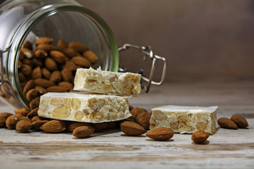 torrone or nougat in front of a glass jar with almonds on a rust
