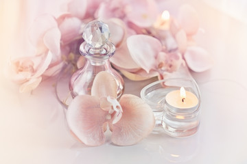 Fototapeta na wymiar Perfume or aromatic oil bottle surrounded by flowers and candles