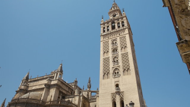 A look at the Giralda Tower with a blue sky, in Seville, from its base to the steeple using a tilt camera move. Seville is in Andalucia, Spain.