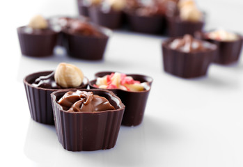 Delicious chocolate candies on white background, close up