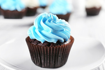 Delicious chocolate cupcake with blue cream on decorated wooden  table, close up