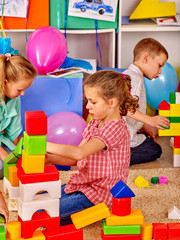 Group children  together are playing with blocks on floor in kindergarten . 