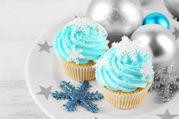 Two tasty blue cupcakes with decorations on light background