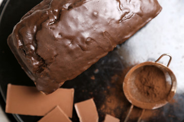 Chocolate cake with icing and cocoa powder on baking dish