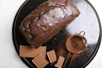 Chocolate cake with icing and cocoa powder on baking dish over white table