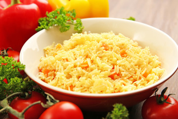 Stewed rice with a carrot on a plate over wooden background, close up