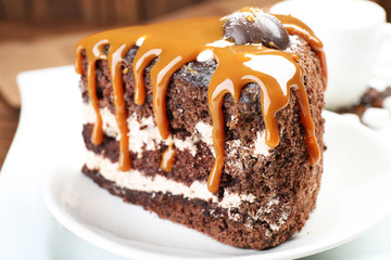 Piece of chocolate cake with caramel in white saucer closeup