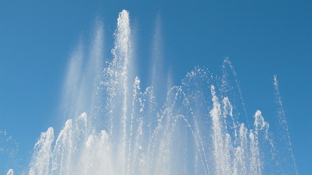 Streams of water from a big fountain with the blue sky as background.