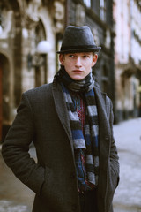 Outdoor portrait of a young handsome man posing on street of the old city. Model wearing stylish...