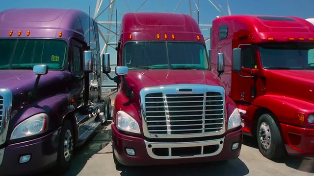 Slow pan down from electric tower to three freight liner trucks parked outdoors