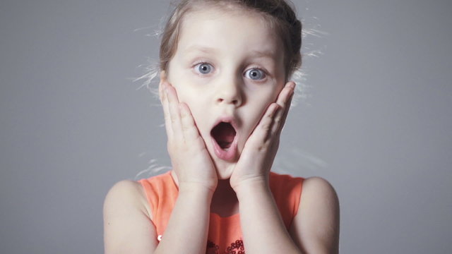 Cute girl with long blonde hair get surprised over gray background.