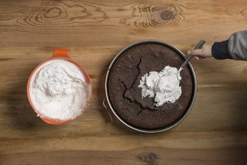 Young kid spreading whipped cream on cake.
