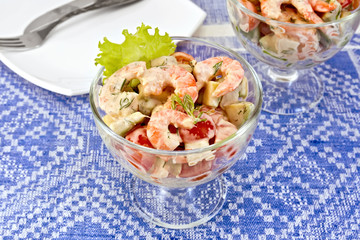 Salad with shrimp and tomatoes on blue tablecloth