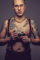 Tattooed man holding old slr camera.