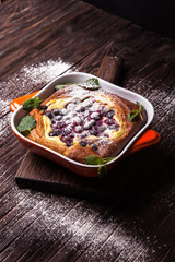 cake with berries in a baking dish, sprinkle with powdered sugar