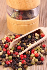 Pepper with spoon and mill on wooden background