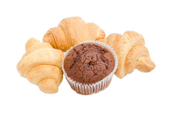 Three small croissant and chocolate muffin on a light background