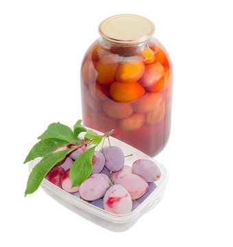 Fresh plums in tray and canned plums in glass jar