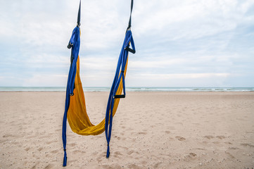 Yellow and blue hammock for aerial or  yoga hanging in the coast