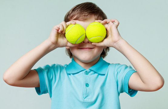  Little boy holding tennis balls instead of the eyes, smiling