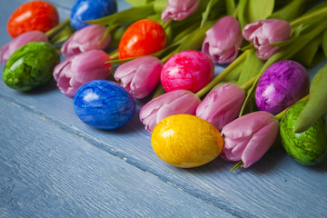 Fototapeta na wymiar Colorful easter eggs with tulips on blue wooden table