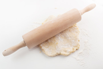 Fototapeta na wymiar Block of freshly made pastry rolled out on a floured work surface with a wooden rolling pin