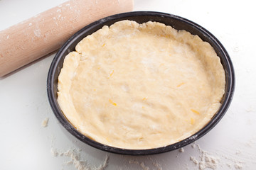 Block of freshly made pastry rolled out on a floured work surface with a wooden rolling pin