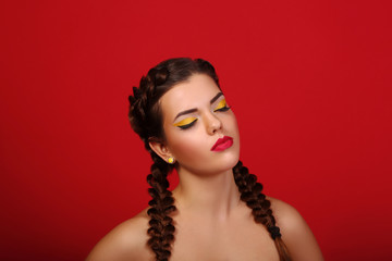 Beauty portrait of beautiful women with long hair brunette with red lips and smoky eyes with closed eyes in studio on a red background