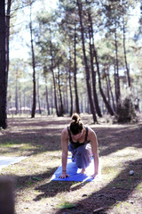 eine Junge Frau macht Yoga auf einer Waldlichtung