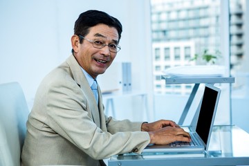 Fototapeta na wymiar Smiling asian businessman working on laptop