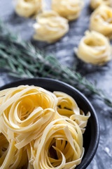 Raw tagliatelle nido on the flour-dusted black wooden background