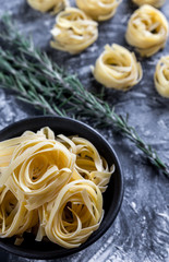 Raw tagliatelle nido on the flour-dusted black wooden background