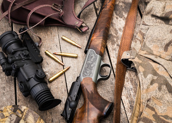 Hunting shotgun and ammunition on wooden background
