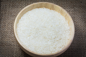 Rice in wooden bowl on Sack or wood table background
