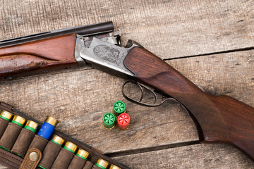 Hunting shotgun and ammunition on wooden background