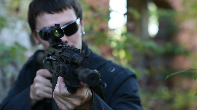 the man in the black jacket aims a gun at the camera, which then slowly passes him on the right, changing the focus with the filter pointing at the person aiming