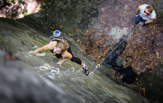 Athletic Young Woman Rock Climbing With Carbines And Rope