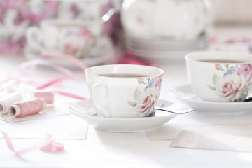 Three cups of tea on a white background. Tea in a bright cups with roses. Vintage style. Bright hues.