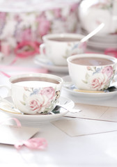 Fototapeta na wymiar Three cups of tea on a white background. Tea in a bright cups with roses. Vintage style. Bright hues.