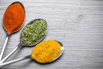 Gray wood and old metal spoons with spices.