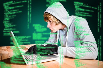 Composite image of focused man with hoodie typing on laptop