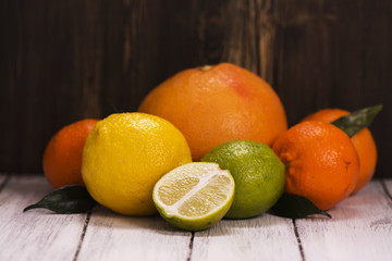 Pile of fresh citrus fruits over wooden background. Lemonade ingredients. Healthy drink concept. Toned image. Selective focus