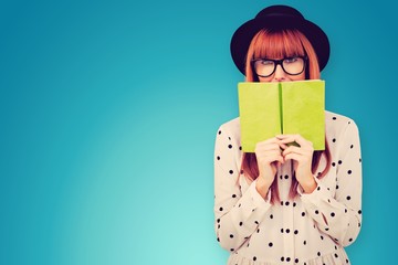 Composite image of hipster woman behind a green book